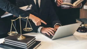 a personal injury lawyer pointing at a laptop while another lawyer is typing on it
