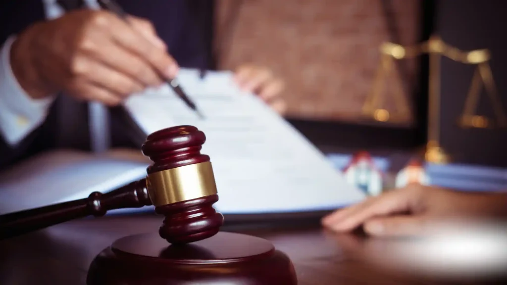 Gavel on a desk with a person signing legal documents in the background.