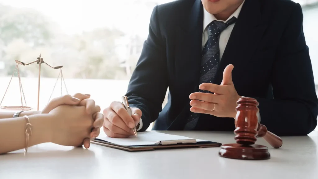 Lawyer discussing case with client at desk with gavel and documents.
