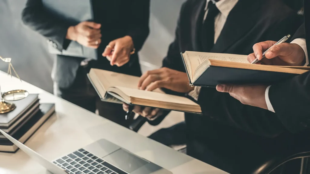 Legal professionals reviewing law books around a laptop
