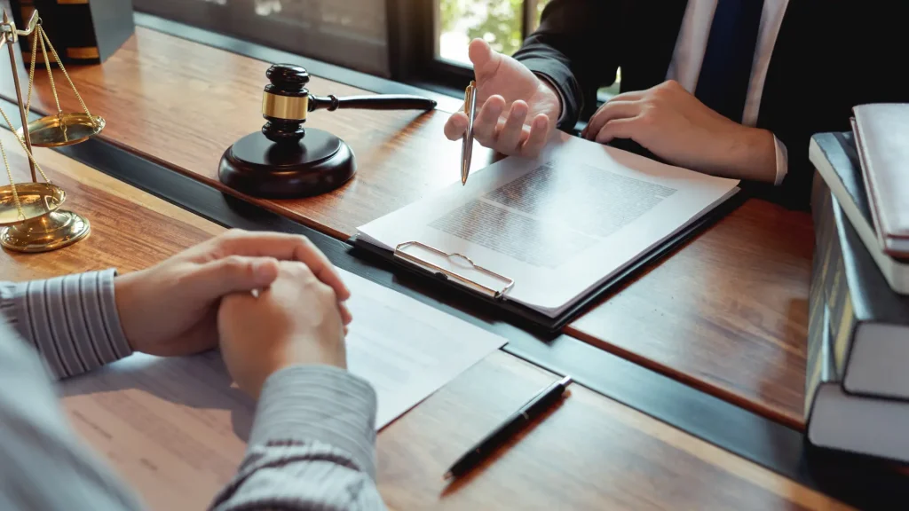 Lawyer reviewing legal document with client at desk with gavel.