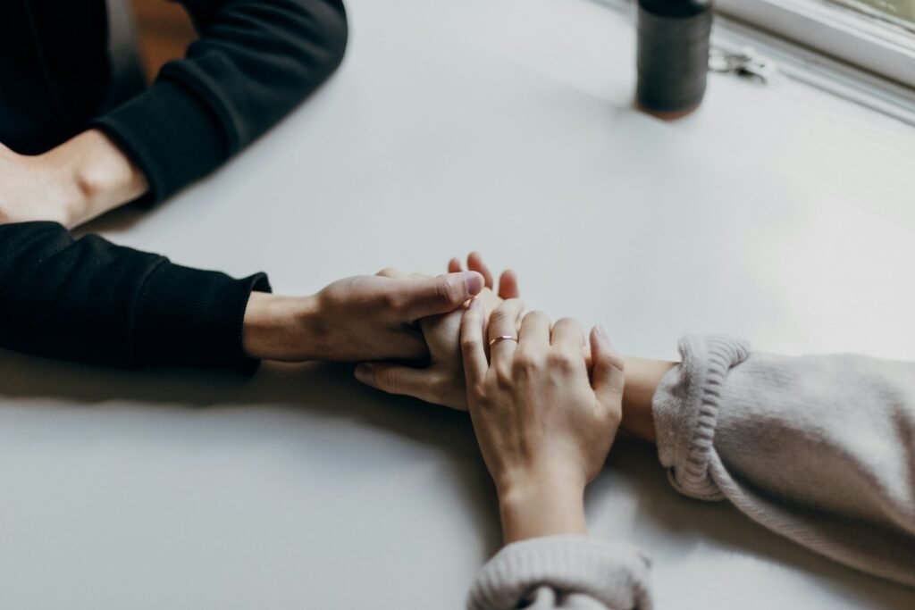 Two people holding hands in comfort after the loss of a loved one