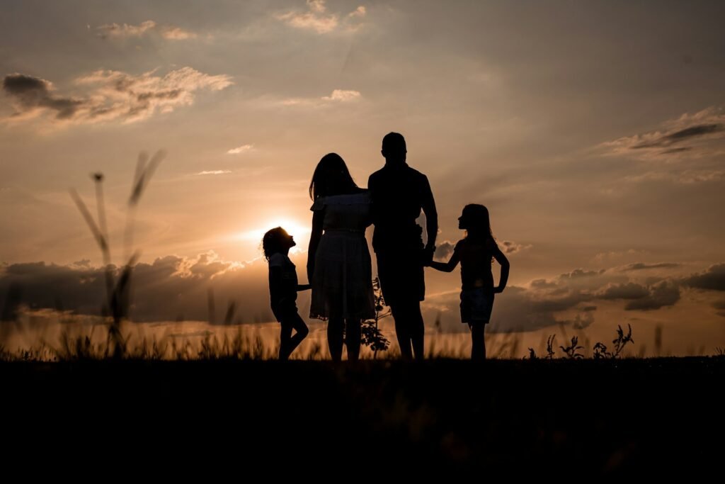Family standing together in a field at sunset